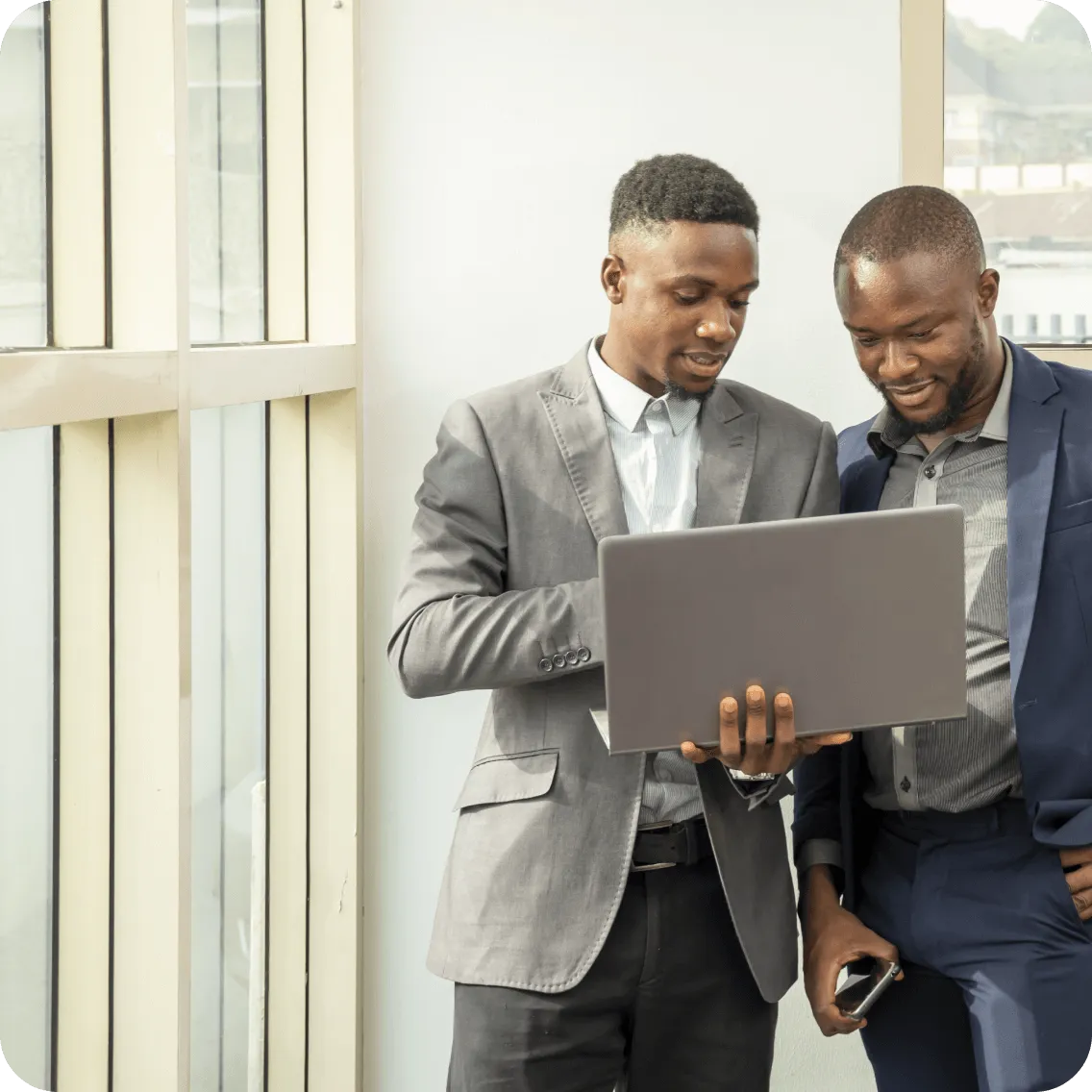 Two men having a conversation while looking at a laptop